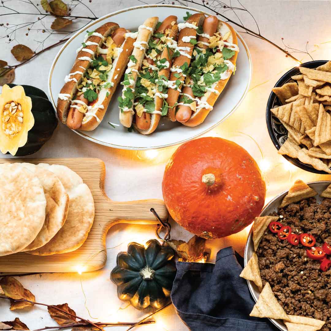 Tarjoiluideat halloweeniin: halloween-kattaus, jossa hot dogeja, pitaleipiä, taco-jauhelihaa ja halloween-kurpitsa